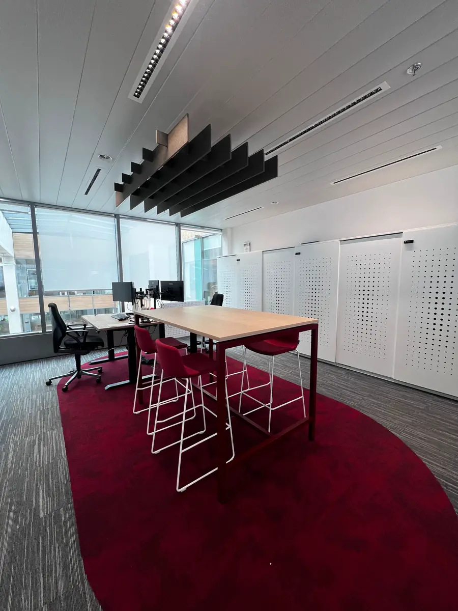 Plateau de bureaux réaménagé avec table haute et tapis rouge