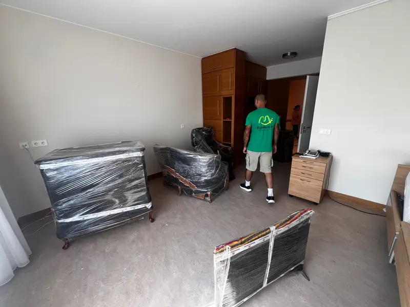 Déménageur en t-shirt vert préparant des meubles emballés