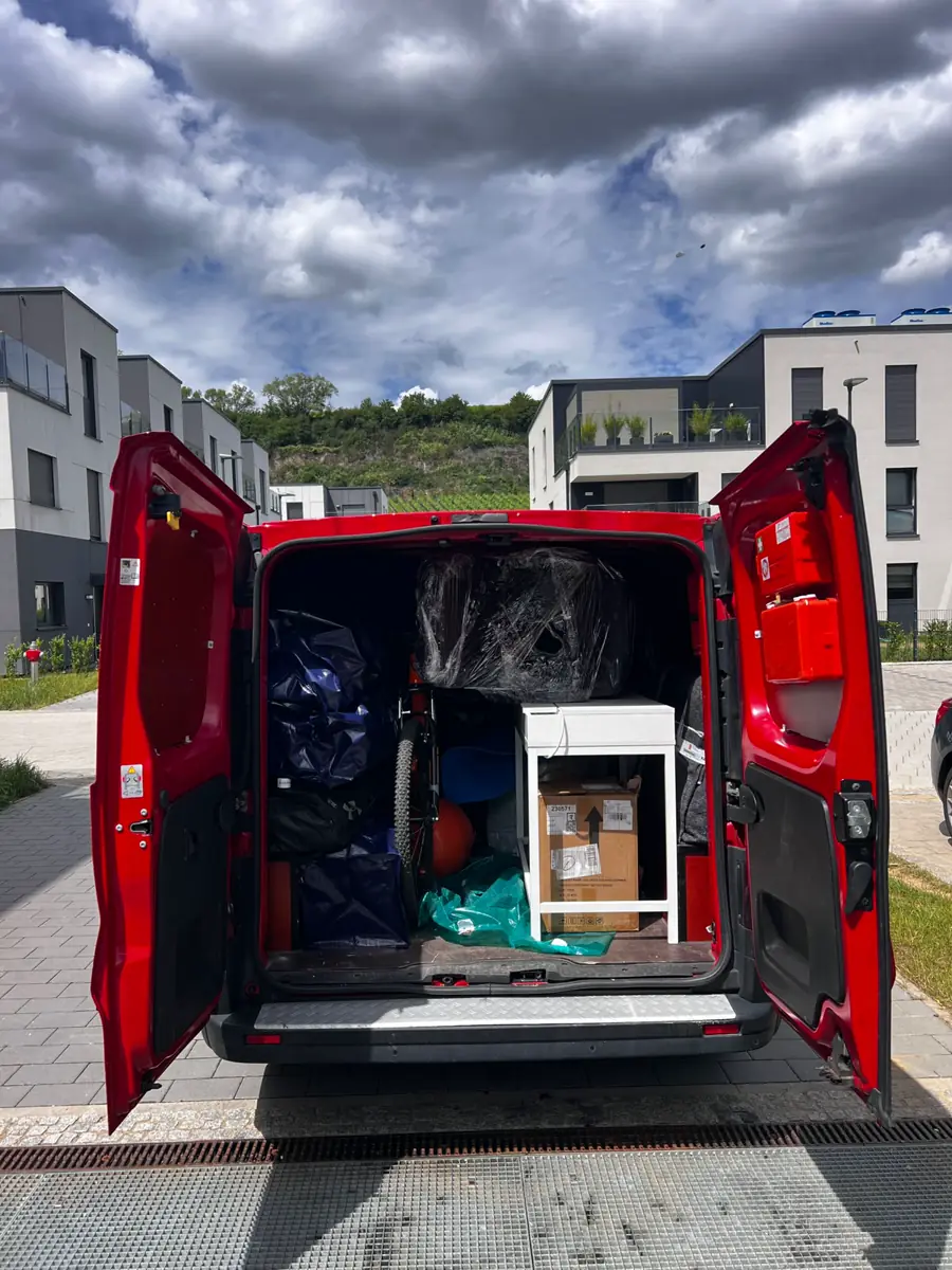 Utilitaire rouge ouvert, chargé de cartons et de meubles